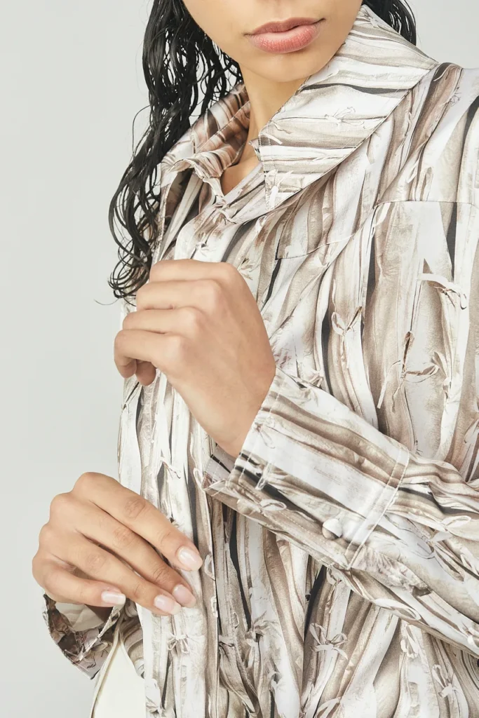 Portfolio Lorenzo Berni_099 - Lorenzo Berni Close-up of a person in a beige, abstract-patterned shirt, adjusting the cuff with both hands.