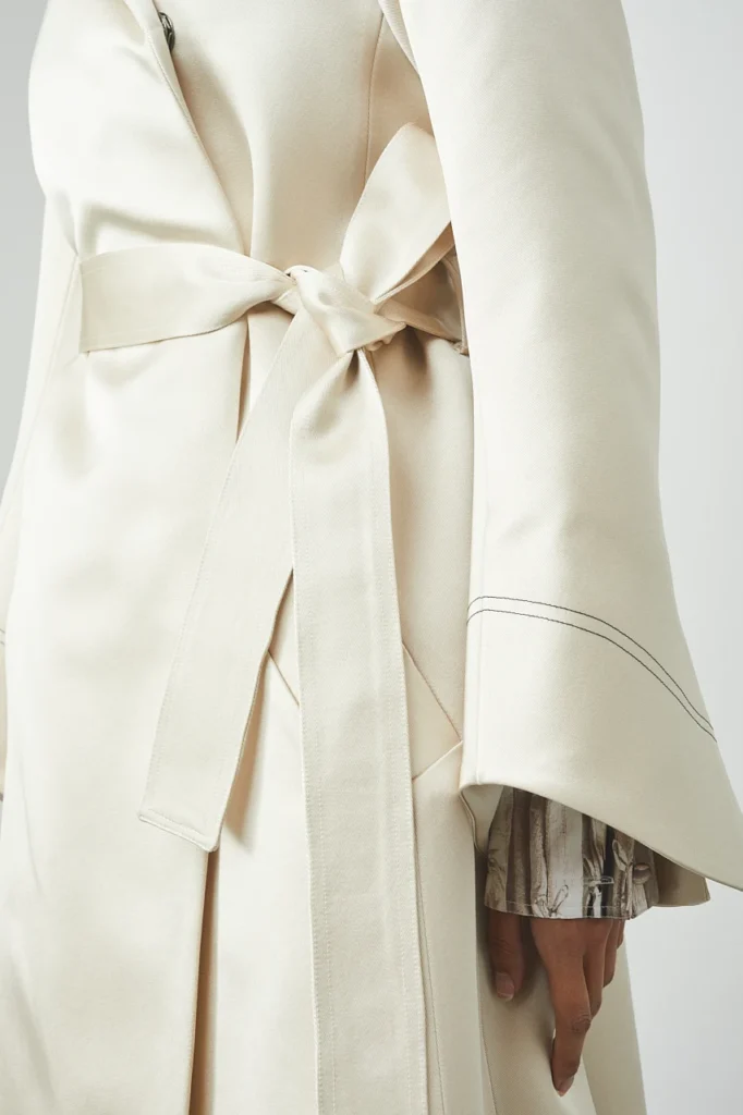 Portfolio Lorenzo Berni_104 - Lorenzo Berni Cream trench coat tied at the waist with a fabric belt, viewed from the back.